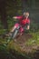 Frontal view of young caucasian male storming with a mountain bike over a berm on a singletrail. Epic ride with a modern mountain