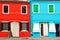 Fronts of the bright red and turquoise houses on the island of Burano, Venice, Italy