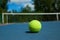 Frontview of bright tennis ball on blue carpet of opened court.