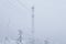 Frosted cell tower and electric wires over a snowy forest on top of a mountain against a winter sky