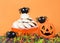 Frosted pumpkin cookies on a pedestal with decorations for Halloween