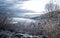 Frosted winter landscape in cold temperature with ice and hoar frost on lake, rime on crisp, frozen leaves and mountains