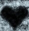 Frosty heart-shaped pattern of ice crystals on a black background. A dark surface with an ice structure allows you to apply or add