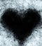 Frosty heart-shaped pattern of ice crystals on a black background. A dark surface with an ice structure allows you to apply or add