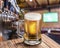 Frosty mug of light beer on the old wooden table. Pub interior and bar counter with beer taps at the background