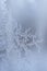 Frosty pattern in form of drawing of elongated ice crystals on frozen winter window.