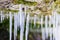 Frosty white icicles hanging from a rocky overhang micro-cave en