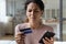 Frown woman holding card and cellphone experiences problems with e-payment