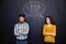 Frowning couple standing after argument over chalkboard background