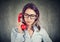 Frowning woman having problem while speaking on red telephone on gray background
