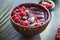 Frozen acai smoothie in coconut shell with raspberries, banana, blueberries,  fruit and granola on concrete background. Breakfast