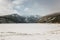 Frozen alpine lake with snow mountains in the background