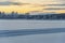 Frozen arctic lake &  forests under an orange sunset sky