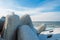 Frozen Baltic sea and concrete tetrapods in sunny winter day. Port entrance and breakwater. Ventspils, Latvia