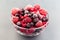 Frozen berries in a glass bowl, raspberry, strawberry, cranberry and black currant, horizontal, closeup