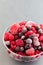 Frozen berries in glass bowl, raspberry, strawberry, cranberry and black currant, vertical, copy space