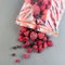 Frozen berries in the plastic bag and on a table, raspberry, strawberry, cranberry and black currant, top view, square