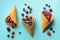Frozen berries - strawberry, blueberry, blackberry, raspberry in waffle cones on blue background. Top view. Banner