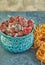 Frozen blackberries with ice in a blue glassware on a wooden board and with hay on a blue background