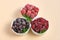 Frozen blueberries, strawberries and raspberries in bowls on a neutral background. Freezing food. Long-term storage