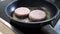 Frozen burger patties burger meat sizzling in hot pan with fat and oil as delicious selfmade hamburger bbq meatballs as unhealthy