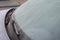 Frozen car windshield covered with ice and snow on a winter day. Close-up view. Close up of frozen windshield and car wiper in