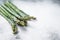 Frozen cold asparagus on a old kitchen table. White background. Top view. Copy space