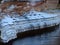 Frozen colorful icicles on the sandstone cliff wall, sunny day on the river bank.