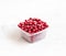 Frozen cranberries in a plastic container on a white background. Storage of frozen food