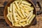 Frozen Crinkle oven French fries potatoes sticks in a wooden plate. Wooden background. Top view