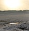 Frozen field with snow and a small ice puddle in the middle of nowhere on a cold clear day in winter