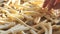 Frozen french fries are laid out by hand on a kitchen baking sheet for cooking in the oven. Slow motion close up view