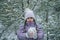 Frozen girl in warm clothes walks in forest with the first long-awaited snow, winter wonderland