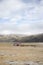 Frozen grassland with single house and misty hills behind on Tibetan Plateau