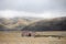 Frozen grassland with single house and misty hills behind on Tibetan Plateau