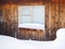 Frozen hut window in winter. Frost on glass. Snow and snowdrifts. Wooden wall of the house. Rural illustration on winter theme