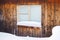 Frozen hut window in winter. Frost on glass. Snow and snowdrifts. Wooden wall of the house. Rustic illustration on winter theme