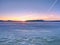 Frozen ice surface on lake with sunset backdrop. Aerial pattern