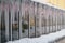 Frozen icicles hanging from roof on glasshouse. Snow melting during early spring and snowbreak