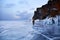 Frozen Lake Baikal at sunset. A male traveler walks on the transparent ice of the lake.