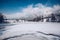 Frozen lake covered in freshly fallen snow with cloud covered hills in the distance