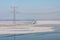 Frozen lake covered with haze and view at power pylon