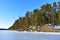 Frozen lake, dense forest and rocky shore
