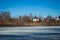 Frozen lake in early springtime with a village in the background