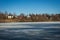 Frozen lake in early springtime with a village in the background