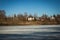 Frozen lake in early springtime with a village in the background