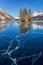 Frozen lake with ice cracks on surface with an islet