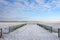 Frozen lake seen from the snowy pier on a chilly day.