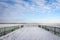 Frozen lake seen from the snowy pier on a chilly day.