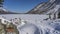 The frozen lake surrounded by mountains is covered with untouched white snow.